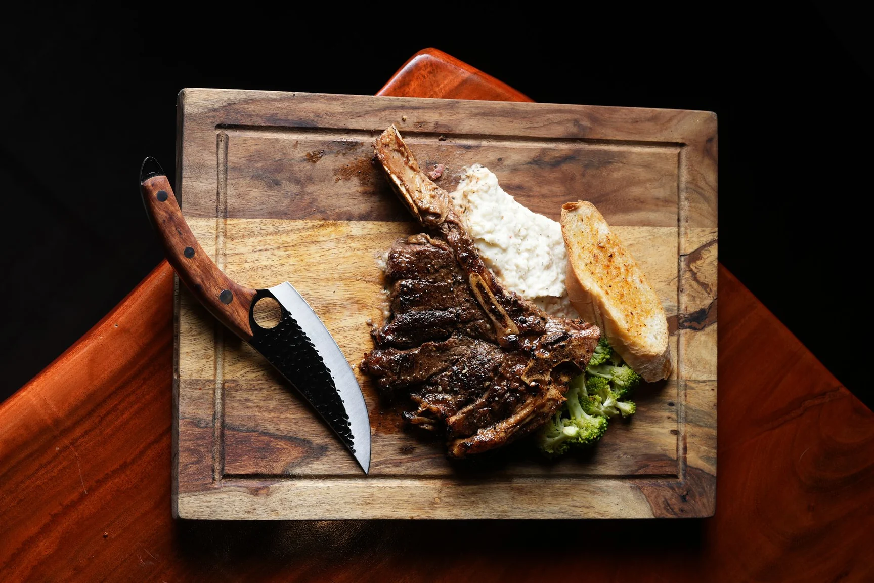 A bone-in steak served on a wooden board at Ninan's